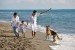 Glückliche Familie mit Hund am Strand spielen