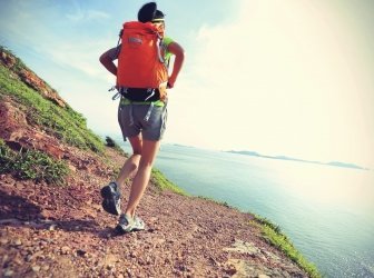 Weibliche Wanderin klettert auf Bergwanderweg am Meer