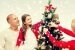Lachende Familie schmückt den Weihnachtsbaum zu Hause