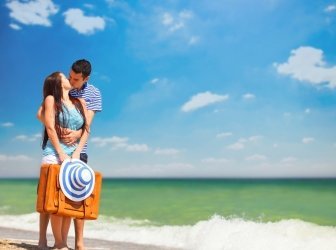 Junges Paar mit Koffer am Strand in Sommertag.