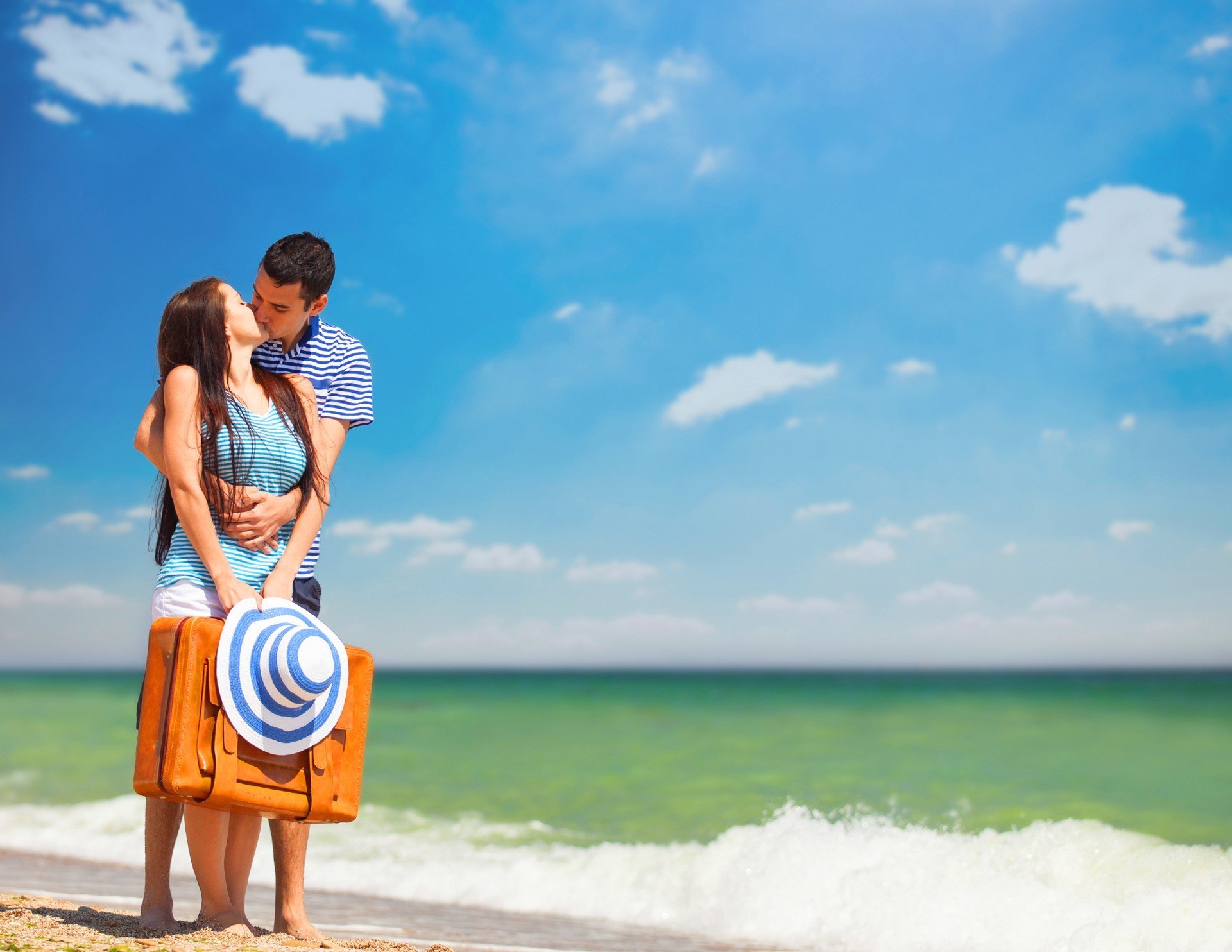 Junges Paar mit Koffer am Strand in Sommertag.