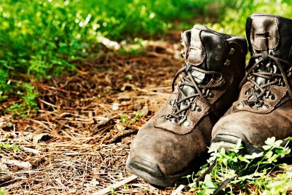 Abgetragene Wanderschuhe neben einem Waldweg