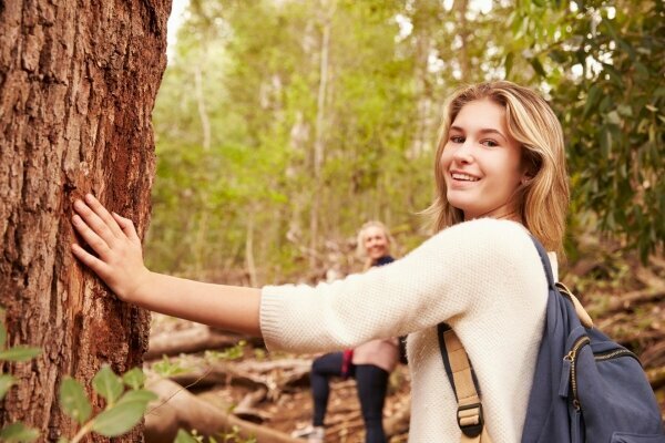 Mädchen, das einen Baum im Wald berührt