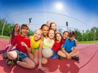 Glückliche Teenager sitzen auf dem Volleyballplatz