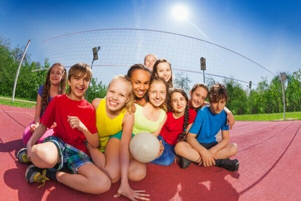 Glückliche Teenager sitzen auf dem Volleyballplatz