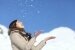 Glückliche Frau wirft Schnee in die Luft im Winter