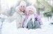 Glückliche Familie Mutter und Tochter sitzen im Schnee im Winter