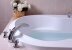 weiße Badewanne mit Wasserhahn und Mosaikfliesen