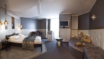 Das Themenzimmer "1001 Nacht Suite mit Whirlpool" soll den Flair des modernen Orients einfangen. Die vorherrschenden Farben sind Gold, Weiß, Erdfarben und Grauflächen kombiniert mit Silber und Farbakzenten.