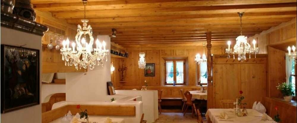 Unsere Ofenstube befindet sich etwas erhöht mit Aussicht in den Wald Richtung Isar. Diese Stube bietet Platz für bis zu 40 Personen und ist urgemtürlich mit viel Holz und schönen Echtkristalllüstern. Dazu der Kachelofen für wohlige Wärme im Winter