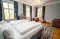 Lichtdurchflutet und weitläufig eröffnet die Blaue Suite den Blick auf den alten Baumbestand des Schlosshotels. Ein separater Ankleidebereich und eine Badewanne zeugen von großzügigen Platzverhältnissen. 