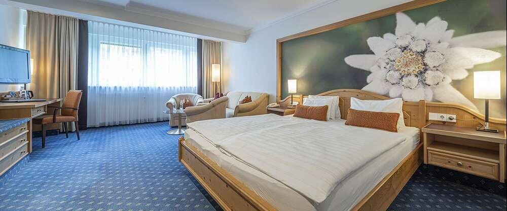 Geräumiges Zimmer auf der 3. Etage, ruhig zur Waldseite gelegen mit großem Doppelbett (180 x 210 cm), gemütlicher Sitzgelegenheit (Couch), Radio, Kabel-TV, Telefon, kostenloses WLAN, Teestation mit Wasserkocher, Minibar (Erstbefüllung kostenfrei) und Zimm