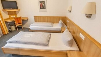 Die Zimmer sind klassisch und gemütlich eingerichtet, was den traditionellen Charakter des Hotels unterstreicht. Die Möbel sind aus Holz gefertigt, was eine warme und einladende Atmosphäre schafft. Die warme Farbgestaltung des Zimmers trägt zusätzlich zur