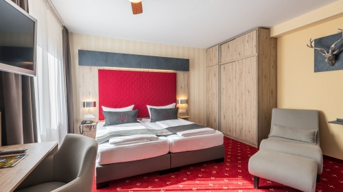 27–33 m² im modernen hochwertigen Stil eingerichtet, Boxspringbetten mit geteilter Matratze (mind. 2x90x200 cm) Flachbild TV, Minibar, Schreibtisch, WLAN, Bad mit Dusche oder Wanne und WC, Fön, Kosmetikspiegel, Pflegeprodukte, gemütliche Sitzecke und Rela