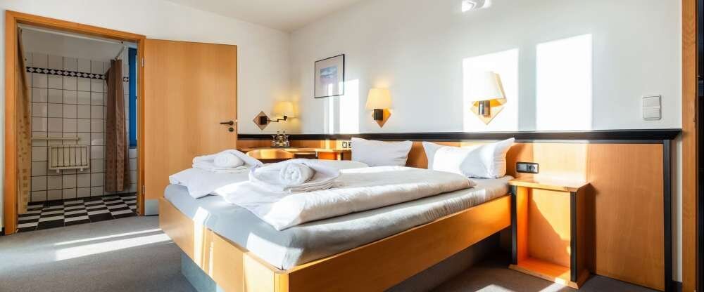 Das Deluxe Doppelzimmer mit Terrasse verfügt über ein komfortables Doppelbett, Kleiderschrank, einen Schreibtisch, Safe, eine Terrasse mit Terrassenmöbeln und Gartenblick sowie ein eigenes Behindertengerechten Bad mit Dusche.