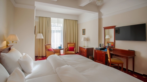 Eleganzzimmer zwischen 18 - 28 m2 mit bezauberndem Blick auf die Kurinsel oder den Hotelgarten. Ein geräumiges Zimmer mit maximalem Komfort dank eines Boxspringbettes in Twin-Size-Größe und einer Matratze aus der exklusiven Luxury Class Kollektion.