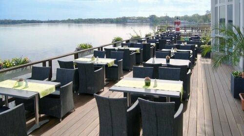 Näher kann man dem Meer nicht kommen. Die Seeterrasse hat 80 Außenplätze und liegt direkt im Zwischenahner Meer. Unter den Stühlen bzw. der Beplankung plätschert das Meer. Ufergras raschelt und läßt den Blick in die Natur schweifen. 