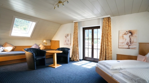 Großzügig geschnittenes Doppelzimmer im Dachgeschoss, nur mit Treppe erreichbar und Blick auf den Wald, Teppichboden, Sofabetten, Dusche/ WC, TV, Fön, Kosmetikspiegel, Schreibtisch, Safe und Balkon .