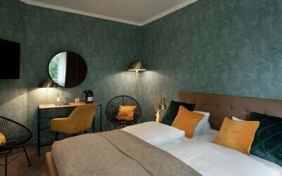 Die Komfort-Doppelzimmer sind geräumiger als die Standard-zimmer mit einem größeren Bett und Ausblick in den Hotelgarten, sowie Schreibtisch, Kaffeemaschine, Snack-Bar, Telefon, Flachbild-TV, Kofferablage, Badezimmer mit WC/ Dusche, Kosmetikspiegel und