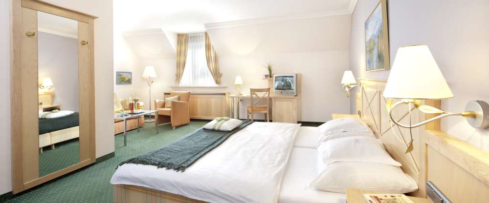 Hell und freundlich ausgestattete Zimmer "Klassik" (21 qm), ausgestattet mit Boxspringbetten ohne Fußteil, Fenster auf den Innenhof oder die Sonnenterrasse, kleiner Kühlschrank, Flachbild-TV. Kleines Bad mit Dusche/WC, Kosmetikspiegel und Kosmet