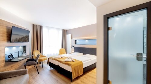 Hier lässt man es sich gut gehen! Äußerst geräumige Zimmer in der 3. Etage mit einer Kaffee-Tee-Station und einem zusätzlichen Sitzbereich mit Sofa und Tisch. Die großflächigen Fensterfronten mit dem französischen Balkon lassen viel Sonne und Licht herein