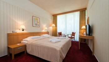 Doppelzimmer zur Einzelnutzung mit stilvoller, funktionaler Einrichtung sowie: Einzelbett, offenem Kleiderschrank, zwei Stühlen und Beistelltisch, LED-TV (Kabel-Sender für TV und Radio), Telefon, Kühlschrank mit Minibar (wird auf Anfrage befüllt), Zimmers