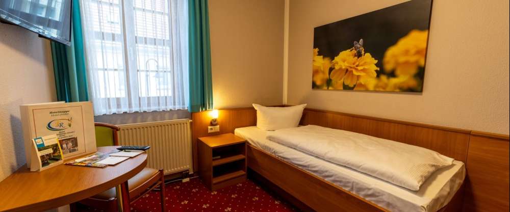 Das freundlich und funktional eingerichtete Einzelzimmer mit ca. 15m² bietet eine angenehme Wohlfühlatmosphäre für Alleinreisende. Das Einzelbett (90 × 200 cm) ist in eine warme Holzverkleidung eingebettet und mit einer Leselampe sowie Steckdosen direkt a