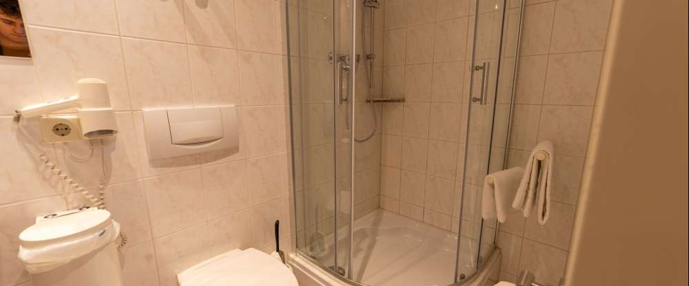 Das freundlich und funktional eingerichtete Einzelzimmer mit ca. 15m² bietet eine angenehme Wohlfühlatmosphäre für Alleinreisende. Das Einzelbett (90 × 200 cm) ist in eine warme Holzverkleidung eingebettet und mit einer Leselampe sowie Steckdosen direkt a