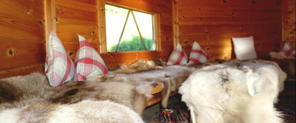 Ruhealp mit Rentierfellen und Blick zur offenen Feuerstelle