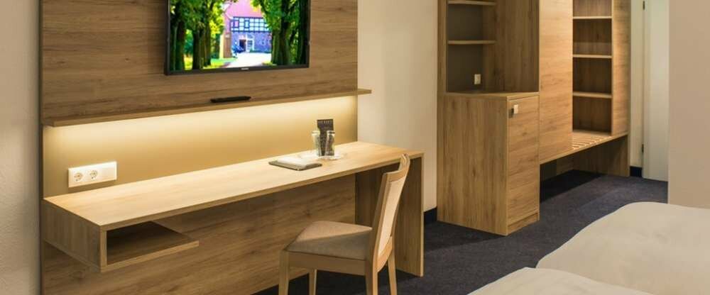 Geräumiges Zimmer mit Schreibtisch, Stühlen, Sitzgelegenheit, LCD TV und Doppelbett. Das Badezimmer ist mit einem großen Spiegel, Dusche und Haartrockner ausgestattet.