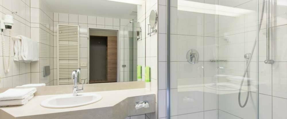 Geräumiges Zimmer mit Schreibtisch, Stühlen, Sitzgelegenheit, LCD TV und Doppelbett. Das Badezimmer ist mit einem großen Spiegel, Dusche und Haartrockner ausgestattet.