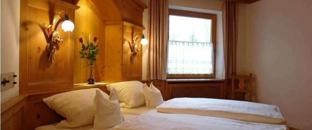 Landhaus Doppelzimmer im Erdgeschoss mit Holzboden und Holzdecke und diagonal gestelltes Bett mit kleiner Sitzecke. Dieses Zimmer befindet sich in Richtung Biergarten.