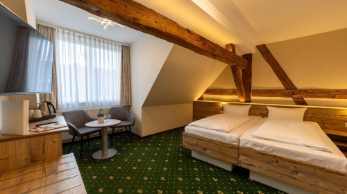 Unsere Premiumzimmer verbinden modernen Komfort mit charmantem Landhausflair. Auf ca. 22m² bis 25m² erwartet Sie ein liebevoll gestalteter Rückzugsort für bis zu 2 Personen, geprägt von sichtbaren Holzbalken, warmen Naturtönen und einer behaglichen Aussta