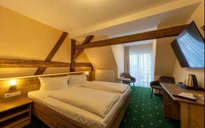 Unser Premiumzimmer mit Balkon verbindet modernen Komfort mit gemütlichem Charme. Auf ca. 17m² bis 25m² erwartet Sie ein liebevoll gestalteter Rückzugsort für bis zu zwei Personen, der durch warme Naturtöne, hochwertige Materialien und sichtbare Holzbalke