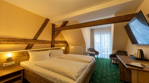 Unser Premiumzimmer mit Balkon verbindet modernen Komfort mit gemütlichem Charme. Auf ca. 17m² bis 25m² erwartet Sie ein liebevoll gestalteter Rückzugsort für bis zu zwei Personen, der durch warme Naturtöne, hochwertige Materialien und sichtbare Holzbalke