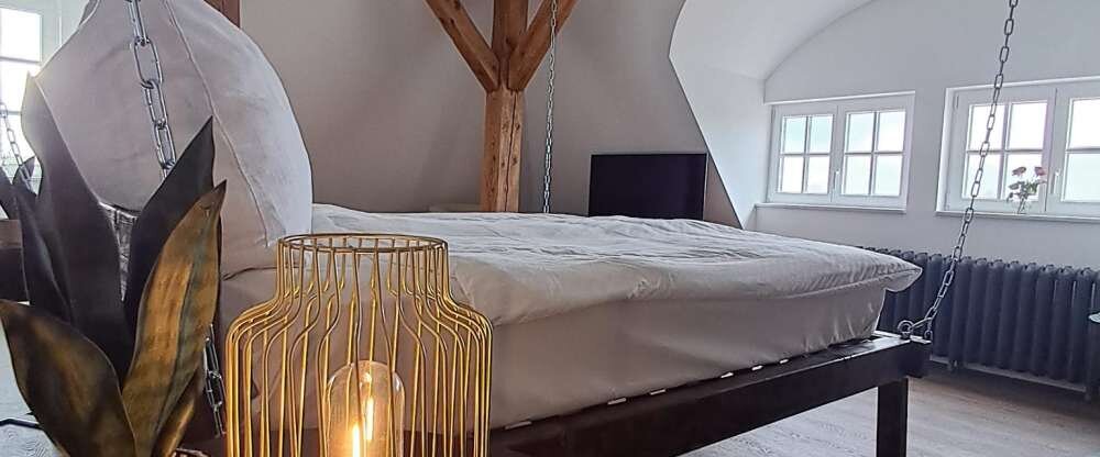 Hier erwartet Sie ein unvergleichliches Erlebnis: Ein exklusives Kingsize-Bett schwingt sanft am Gebälk unter dem Dach des historischen Schlosses und bietet eine romantische Atmosphäre, die Sie nie vergessen werden. Romantik & Luxus: Genießen Sie d