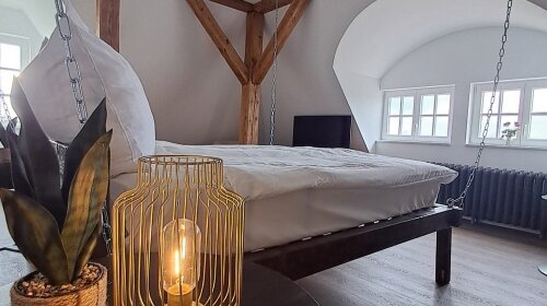 Hier erwartet Sie ein unvergleichliches Erlebnis: Ein exklusives Kingsize-Bett schwingt sanft am Gebälk unter dem Dach des historischen Schlosses und bietet eine romantische Atmosphäre, die Sie nie vergessen werden.

Romantik & Luxus: Genießen Sie d