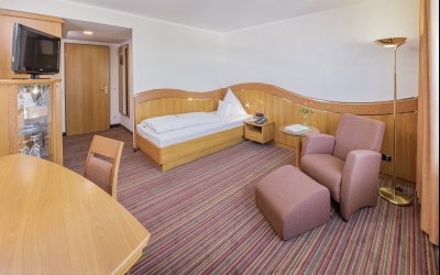 24 m², Einzelbett (210x100), Schreibtisch mit Stuhl, Glastisch mit Sessel, kostenloses WLAN, Minibar, Safe, Kofferbock, großzügiger Kleiderschrank, 80cm Flat-TV mit über 70 mehrsprachigen Sendern, zur Bahnhofseite gelegen. Alle Zimmer mit Dusche und/ ode