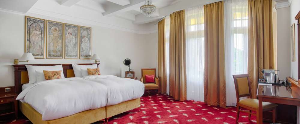 Exklusive Suite mit 53 m2 mit Werken des Künstlers Alfons Mucha, in der Kunst und Eleganz auf den Komfort der modernen Zeit treffen. Die Suite bietet einen eleganten Wohnbereich mit einem Schlafsofa, ein geräumiges Schlafzimmer, das mit Reproduktionen von