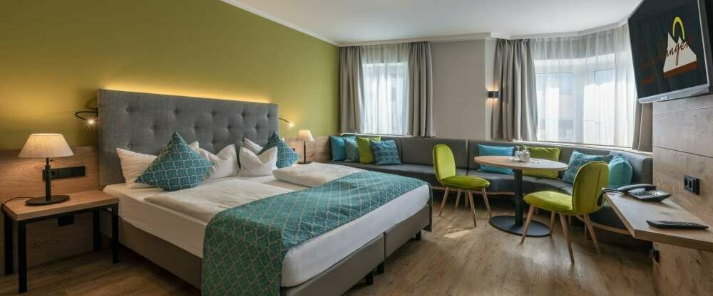 Neugestaltete Suite mit einem Schlafzimmer mit gemütlicher Sitzecke und eim Wohnzimmer mit einer Couch die zum Etagenbett umfunktioniert werden kann.