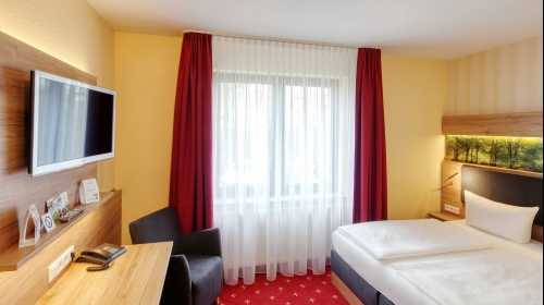 16-23 m² im modernen englischen Stil eingerichtet, Boxspringbett (160×200 cm / 80×200 cm), Flachbild TV, Minibar, Schreibtisch, WLAN, Bad mit Dusche und WC, Fön, Kosmetikspiegel, Pflegeprodukte, Sitzgelegenheit mit Tisch und Stühlen, bequem ebenerdig oder