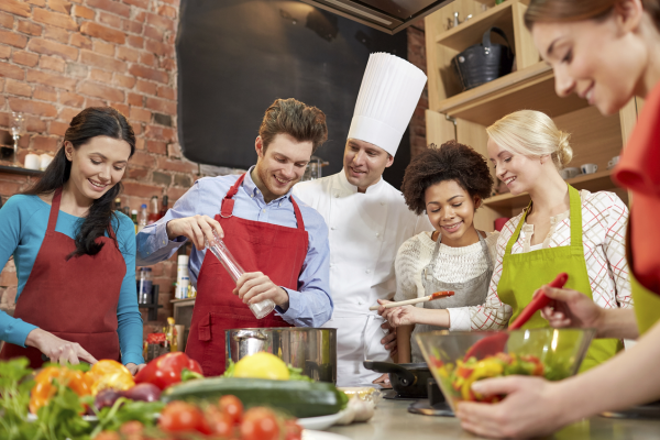 Glückliche Freunde und Chefkoch kochen in der Küche